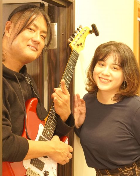 ギターを持ったギターの田村太一先生と再会する音楽教室スタッフきゃな