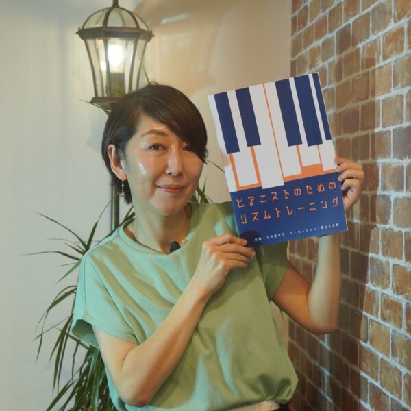 「ピアニストのためのリズムトレーニング」教則本を掲げる作曲家小野田享子さん